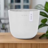 Oslo Eco Pot in White on timber table with a green plant in the background